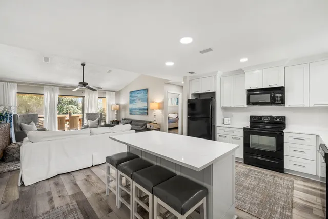 a large kitchen with kitchen island a stove a sink a oven a dining table and chairs