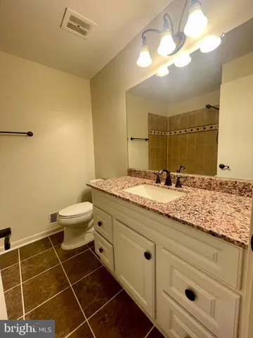 a bathroom with a granite countertop sink a toilet and a mirror