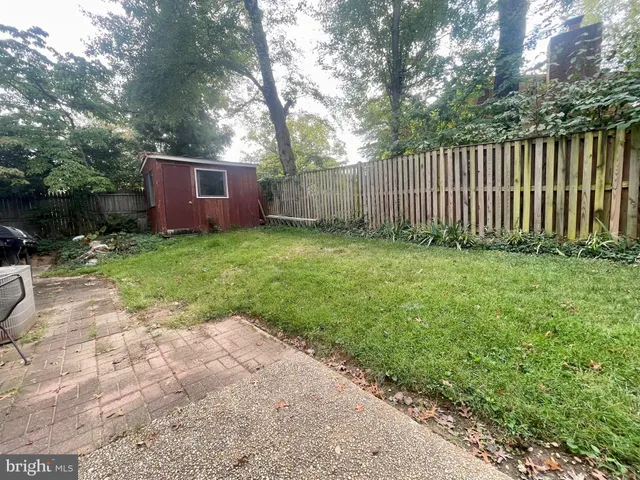 a view of a backyard with wooden fence and large trees