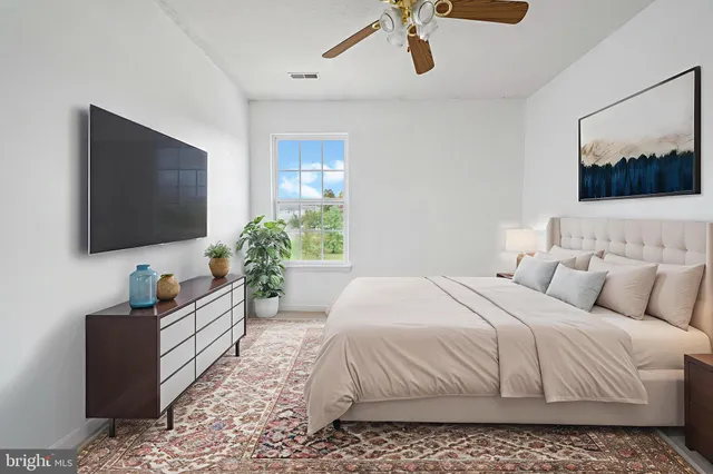 a bedroom with a bed a couch and a flat screen tv