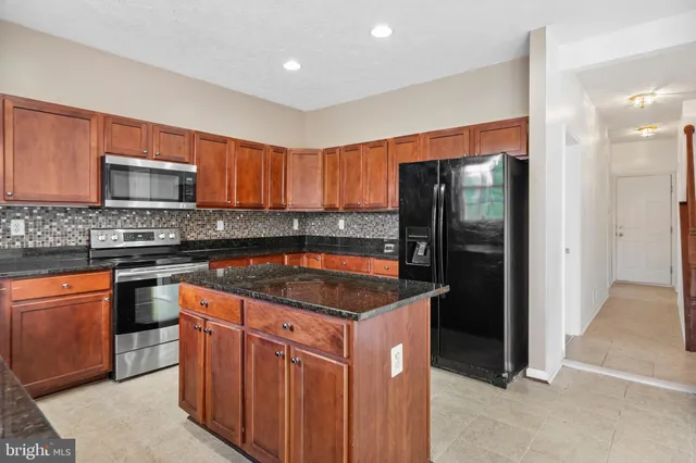a kitchen with stainless steel appliances granite countertop a stove a refrigerator and a sink