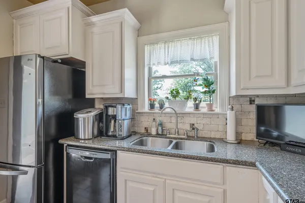 a kitchen with stainless steel appliances granite countertop a sink a refrigerator and a granite counter tops