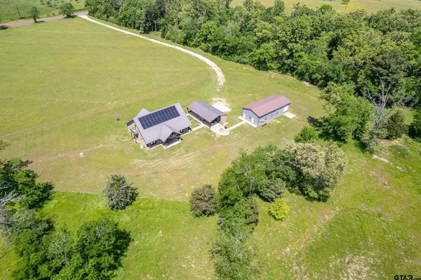 an aerial view of residential houses with outdoor space and trees all around