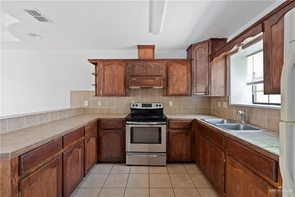 a kitchen with a sink stove top oven and cabinets