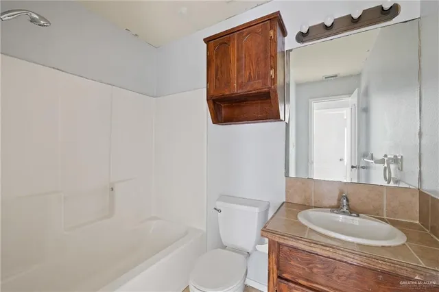 a bathroom with a granite countertop sink mirror vanity and toilet