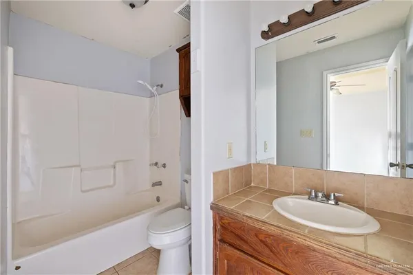 a bathroom with a granite countertop sink toilet mirror and shower