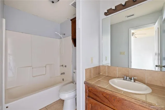a bathroom with a granite countertop sink toilet mirror and shower