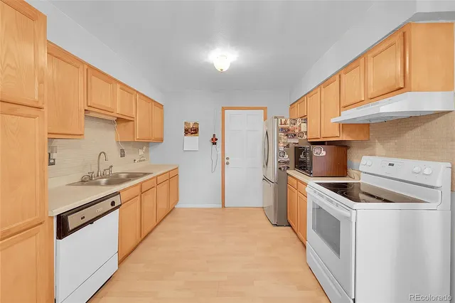 a kitchen with stainless steel appliances a stove top oven a sink a refrigerator and cabinets