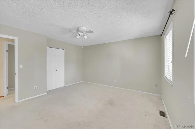 an empty room with a chandelier fan and windows