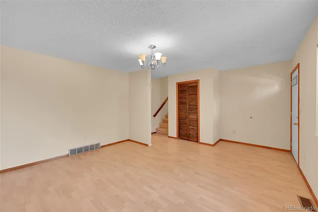a view of an empty room with chandelier fan