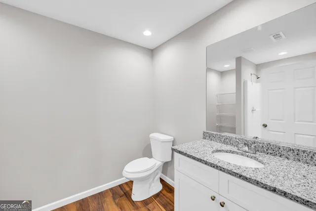 a bathroom with a granite countertop sink a toilet and a mirror
