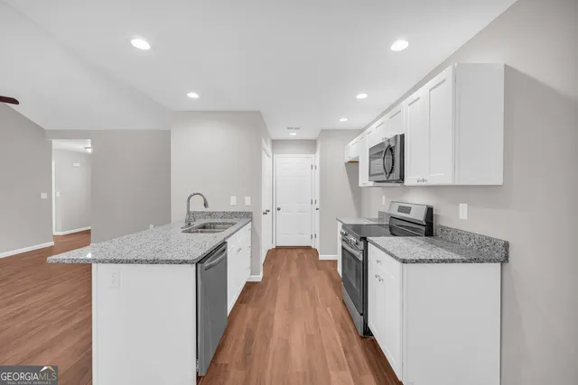 a kitchen with granite countertop a sink a counter top space stainless steel appliances and cabinets