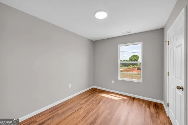 an empty room with window and wooden floor