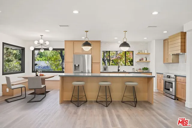 a large kitchen with stainless steel appliances granite countertop a large window a oven and white cabinets