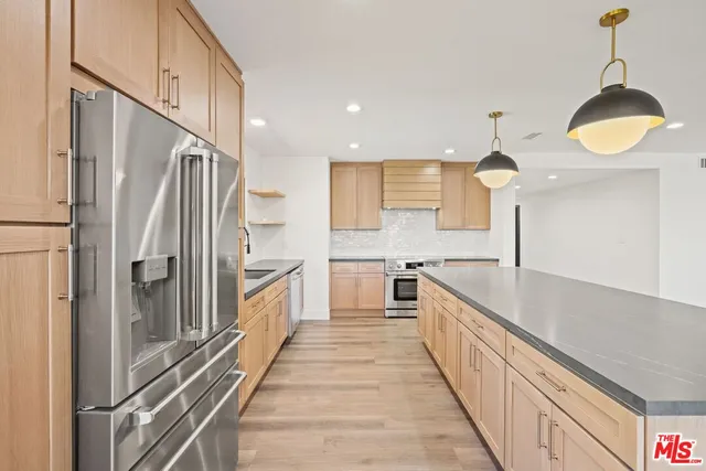 a kitchen with stainless steel appliances granite countertop a sink a stove and a wooden floors