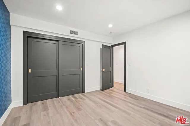 a view of a hallway with wooden floor and a bathroom