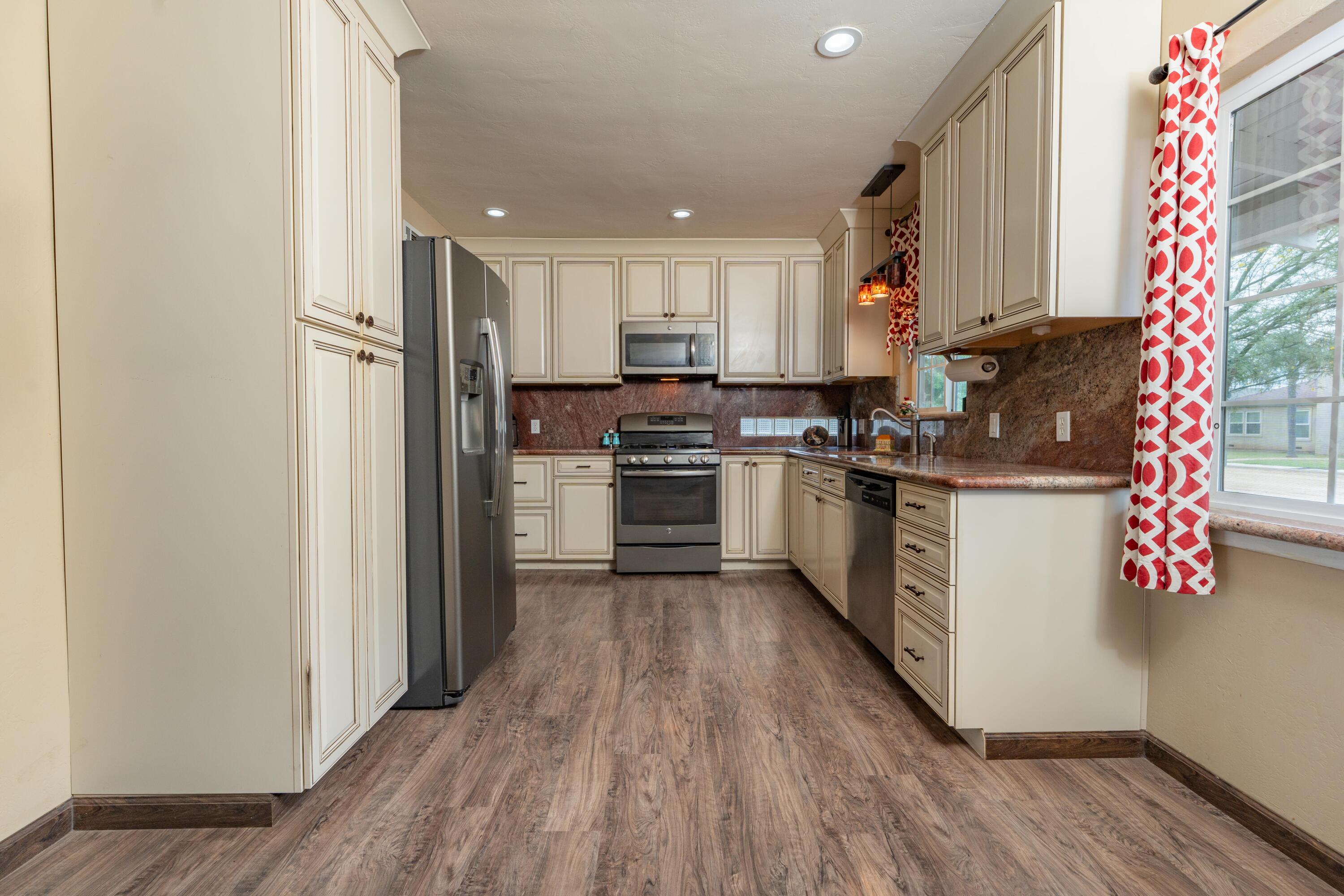 570 North Birch Avenue Reedley, CA 93654 - Photo 12 of 52 a kitchen with kitchen island wooden floors appliances and cabinets
