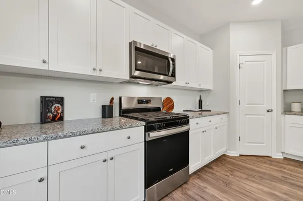 a kitchen with stainless steel appliances granite countertop white cabinets granite counter tops and a hard wood floors