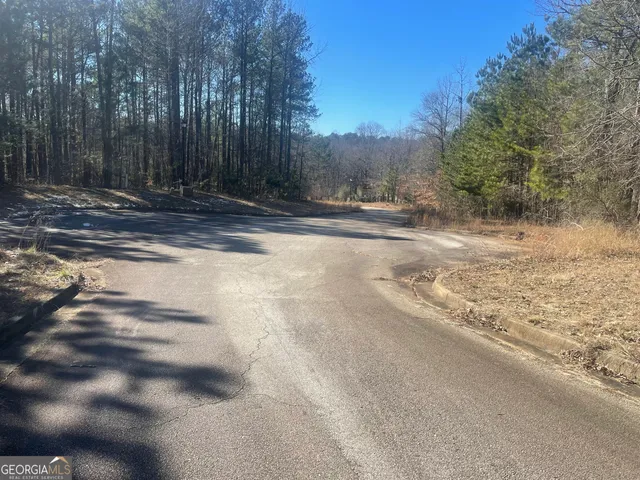 a view of a yard with trees and a wooden fence