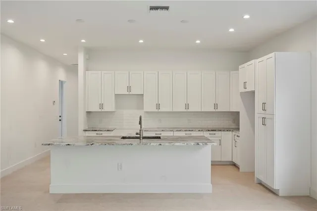 a kitchen with kitchen island white cabinets and stainless steel appliances