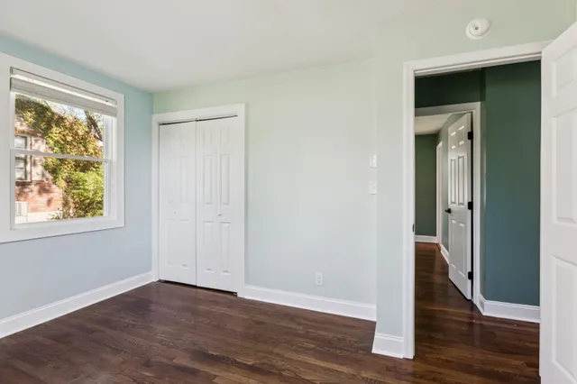 an empty room with wooden floor and window