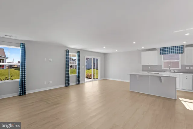 a view of an empty room with kitchen and a window