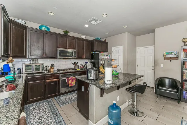 a kitchen with stainless steel appliances granite countertop a stove refrigerator sink and cabinets