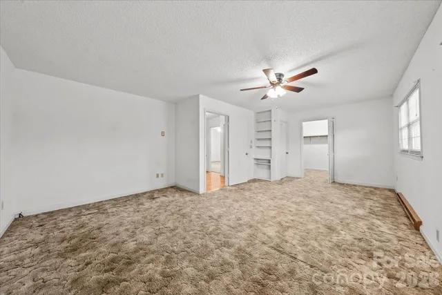 an empty room with fan and windows