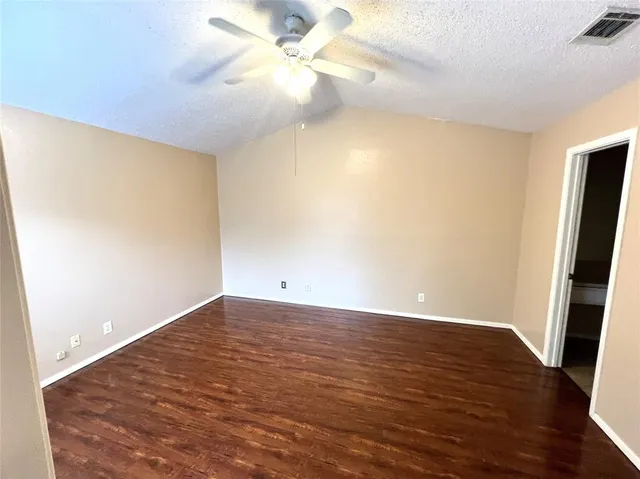 an empty room with wooden floor and fan