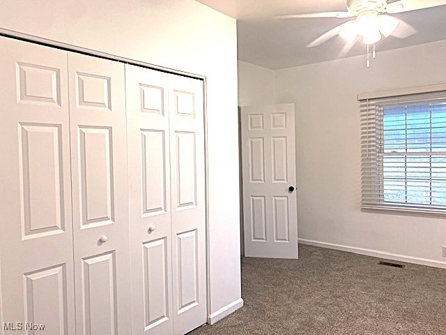 71056 Morristown Flushing Road Flushing, OH 43977 - Photo 11 of 15 Unfurnished bedroom featuring a closet, dark carpet, and a ceiling fan