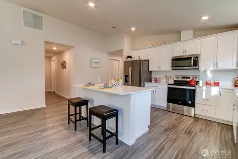 a kitchen with stainless steel appliances kitchen island granite countertop a stove a sink and a microwave