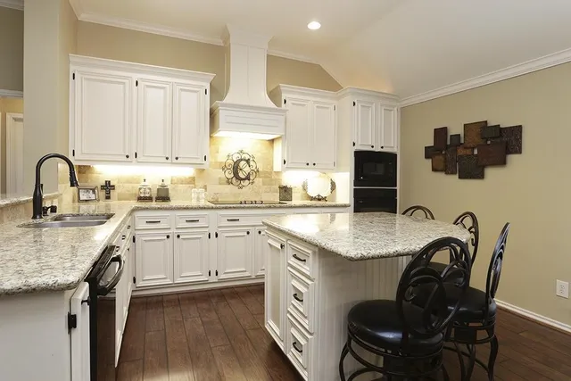 a kitchen with granite countertop white cabinets and chairs