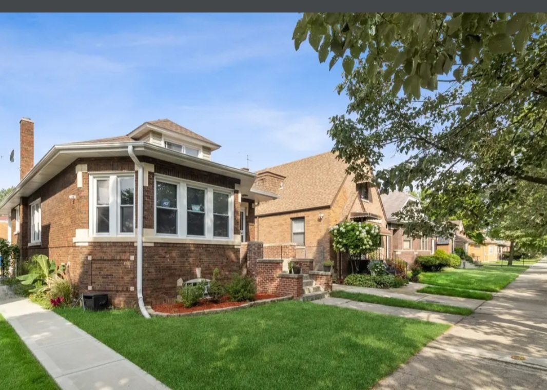 Undisclosed Address Chicago, IL 60628 - Photo 3 of 27 a front view of a house with a garden and plants