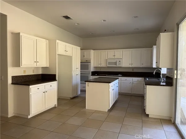 a kitchen with a refrigerator and white cabinets