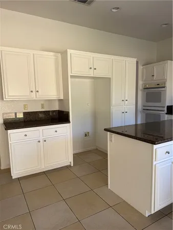 a kitchen with granite countertop white cabinets and white appliances