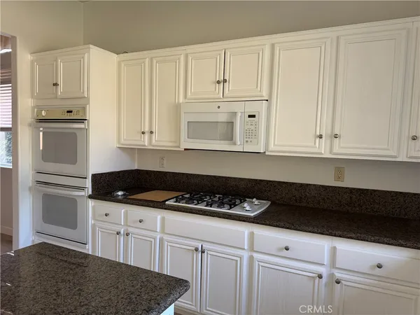a kitchen with granite countertop white cabinets and refrigerator