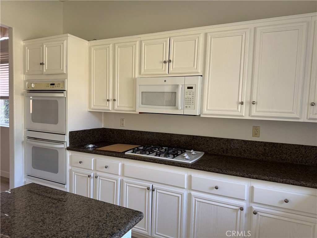 13628 Jeremy Court Rancho Cucamonga, CA 91739 - Photo 9 of 29 a kitchen with granite countertop white cabinets and refrigerator
