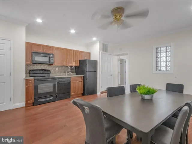 a kitchen with stainless steel appliances kitchen island granite countertop a sink a stove a dining table and chairs