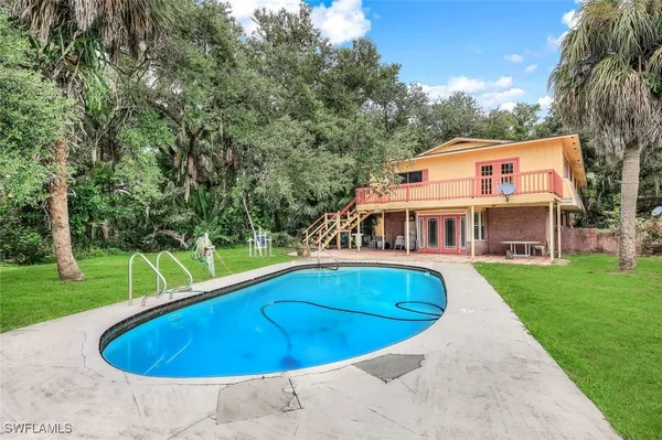 a view of house with swimming pool and yard
