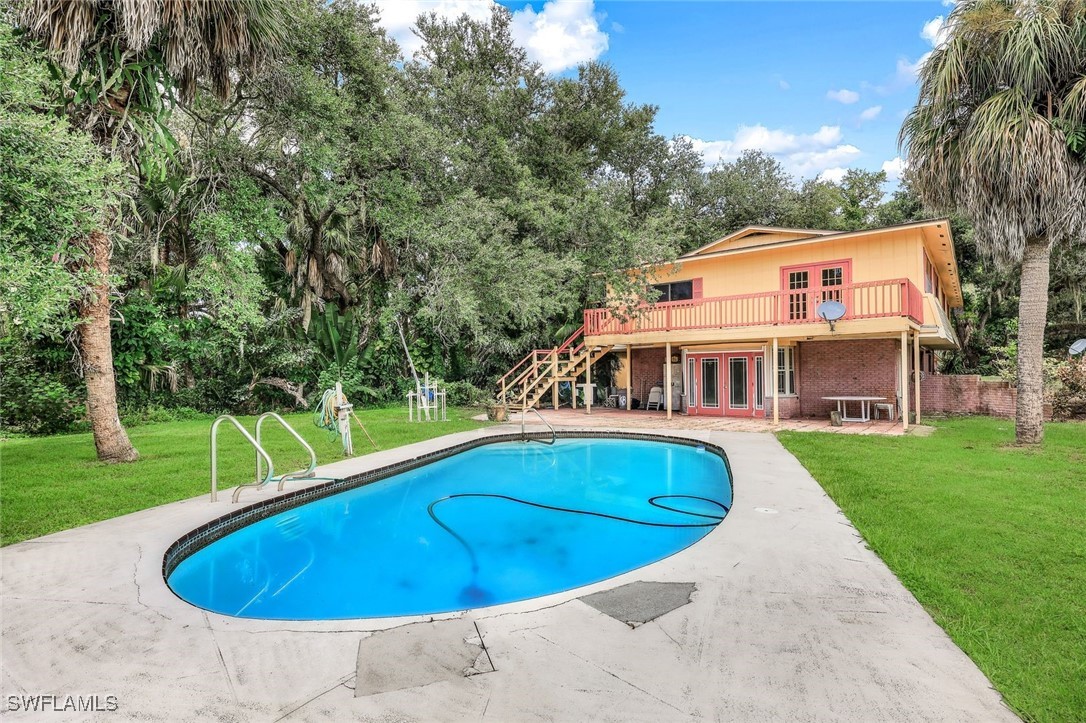 a view of house with swimming pool and yard