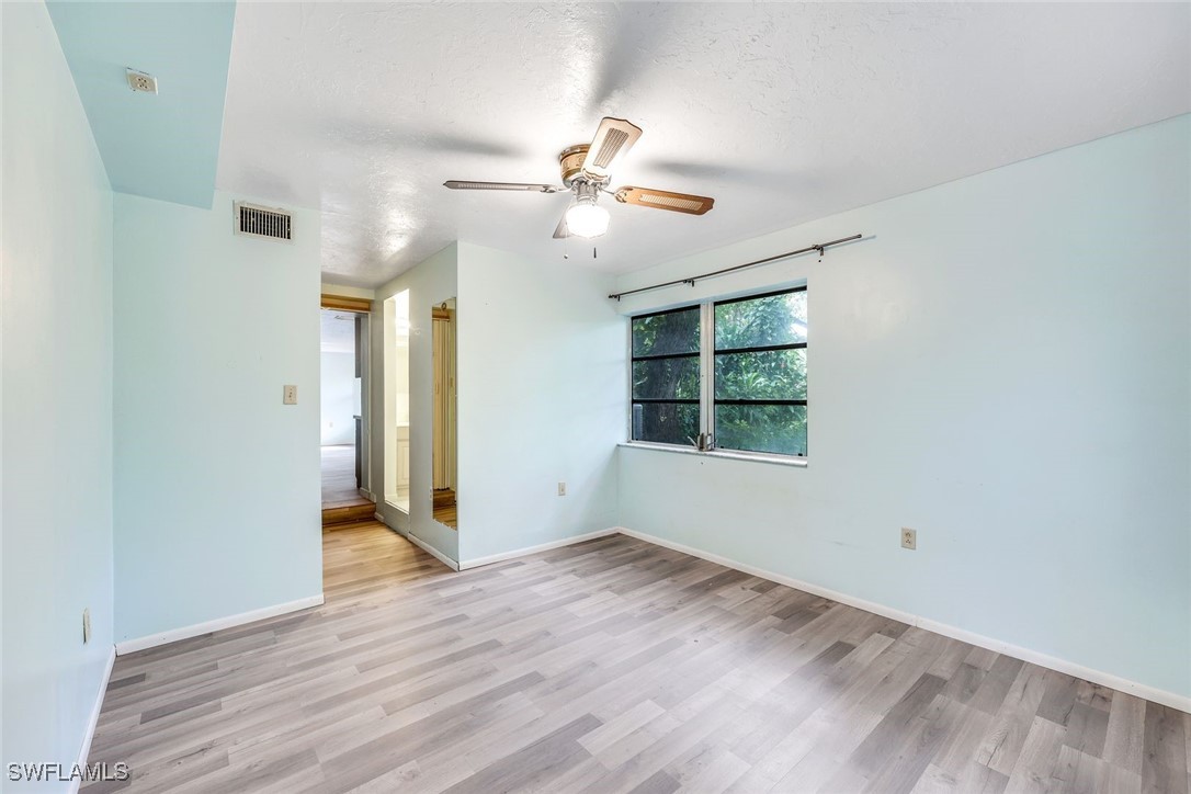 18191 Slater Road North Fort Myers, FL 33917 - Photo 23 of 34 an empty room with wooden floor ceiling fan and windows