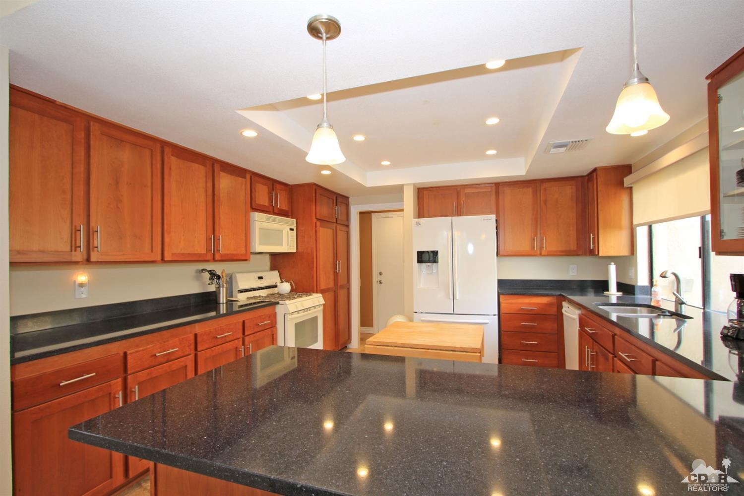72350 Rodeo Way Rancho Mirage, CA 92270 - Photo 9 of 44 a kitchen with stainless steel appliances granite countertop a stove a sink and a refrigerator with wooden cabinets