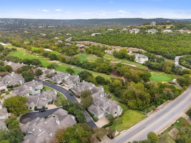 an aerial view of residential houses with outdoor space and trees