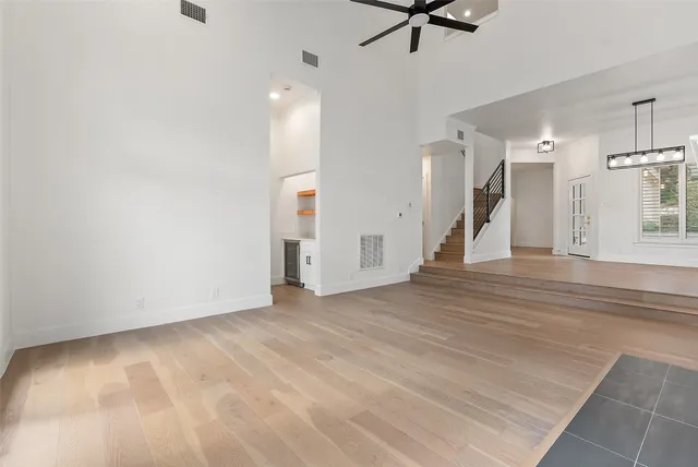 a view of an empty room with wooden floor and a ceiling fan