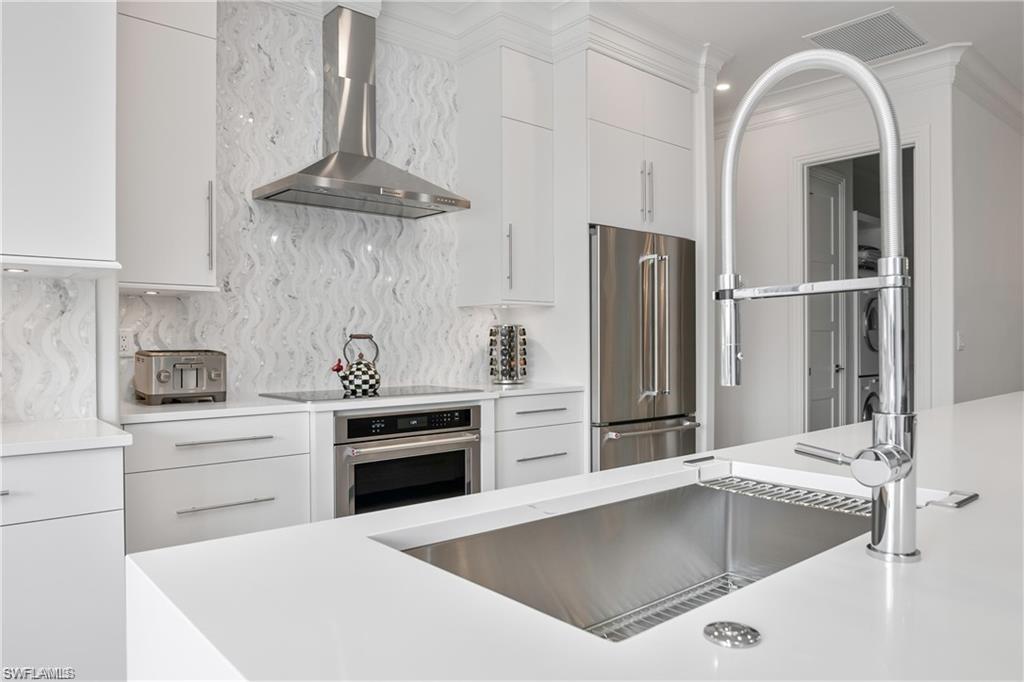 8967 Lely Island Circle Naples, FL 34113 - Photo 21 of 46 a kitchen with a stove a refrigerator and cabinets