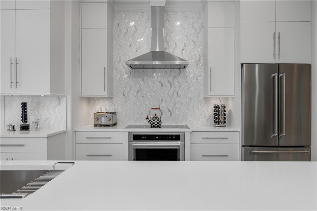 8967 Lely Island Circle Naples, FL 34113 - Photo 22 of 46 a kitchen with stainless steel appliances granite countertop a stove a refrigerator and a white cabinets