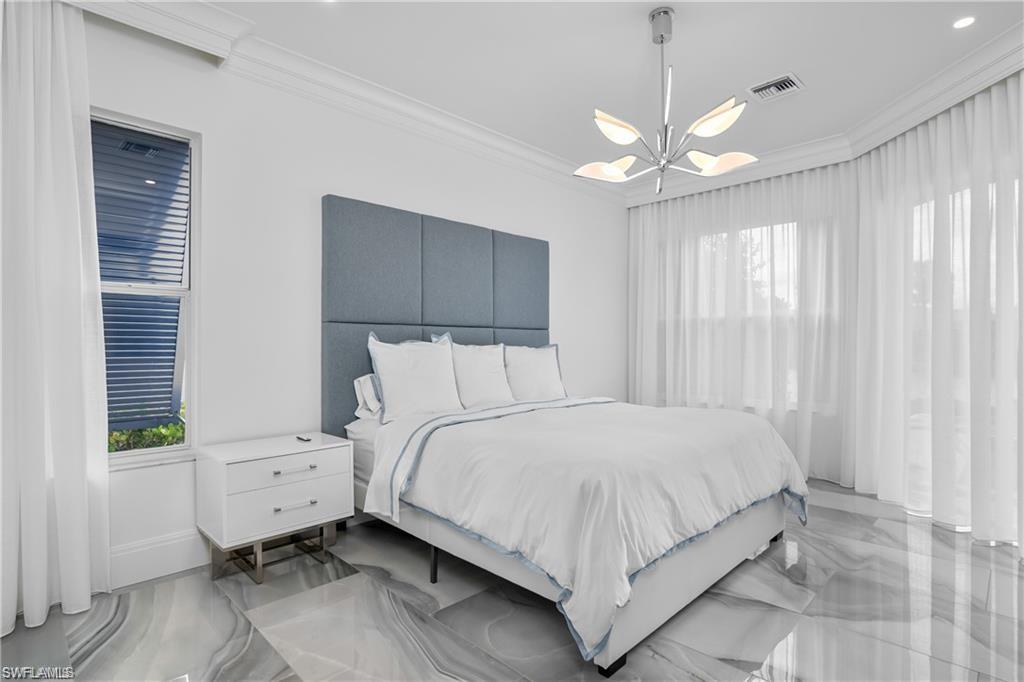 8967 Lely Island Circle Naples, FL 34113 - Photo 30 of 46 a bedroom with a large bed chandelier and a window