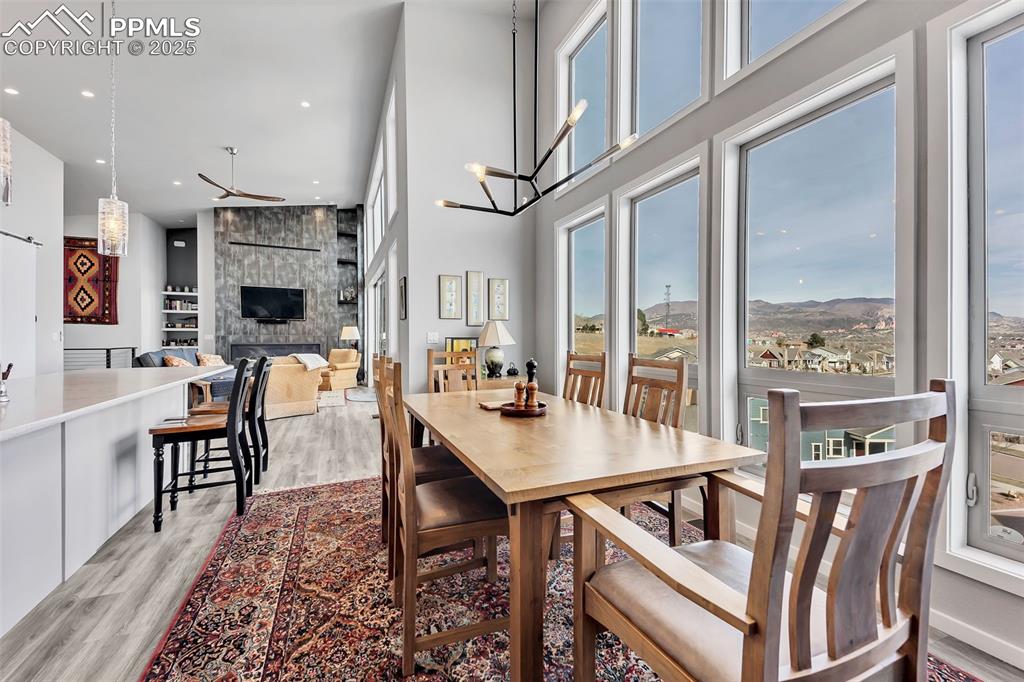 414 Eclipse Drive Colorado Springs, CO 80905 - Photo 11 of 50 Dining room featuring a wealth of natural light, a high ceiling, light wood-style floors, and a large fireplace