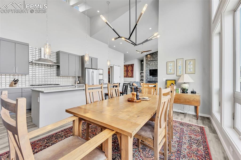 414 Eclipse Drive Colorado Springs, CO 80905 - Photo 12 of 50 Dining area featuring baseboards, light wood-type flooring, a high ceiling, and a notable chandelier