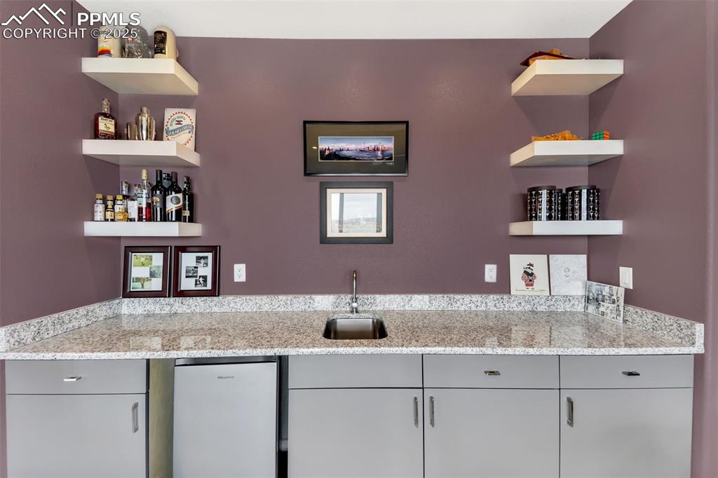 414 Eclipse Drive Colorado Springs, CO 80905 - Photo 28 of 50 Bar featuring indoor bar, a sink, and stainless steel fridge